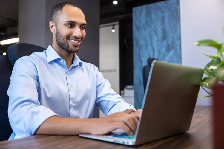 an African professional working on a laptop in a modern business environment